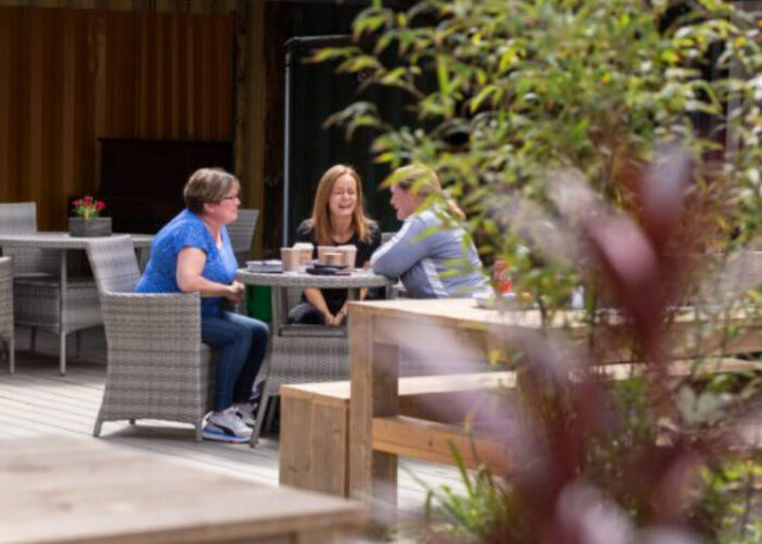 Three Women Sitting At Outdoor Cafe Table