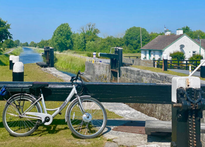 Silver bicycle parked beside a scenic canal lock