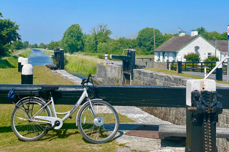 Silver bicycle parked beside a scenic canal lock