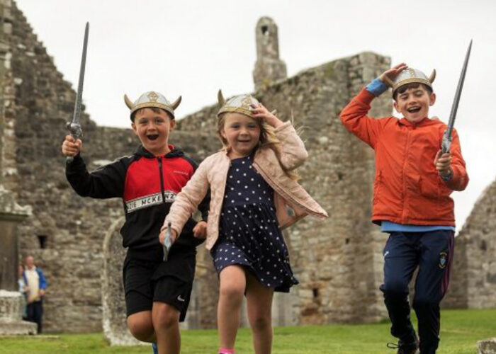Three Children Playing With Viking Helmets And Swords