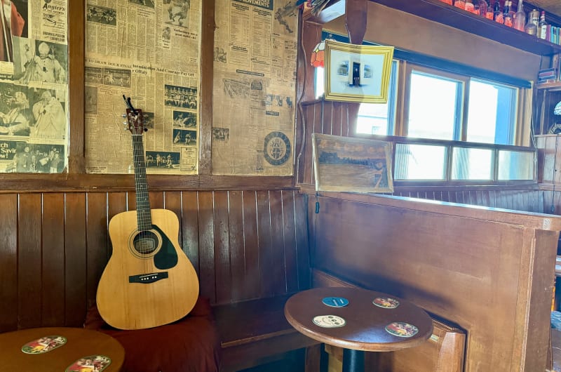 Acoustic guitar leaning against booth in rustic pub