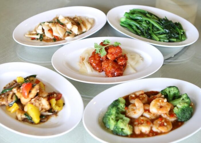 Assorted stir fried Chinese dishes on white plates