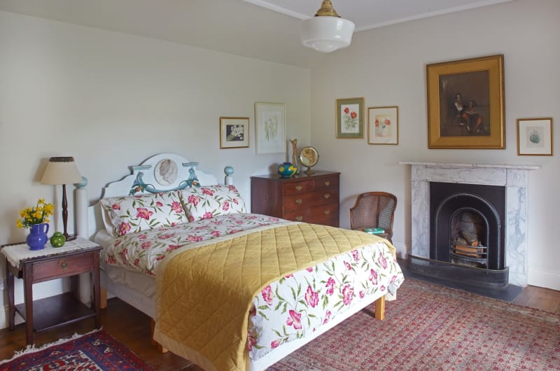 Bedroom with floral bedding fireplace and antique furniture