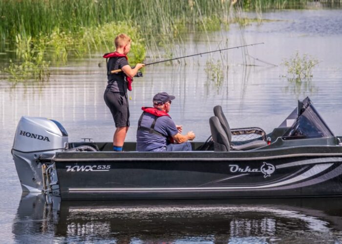 Boy And Man Fishing On Motorboat