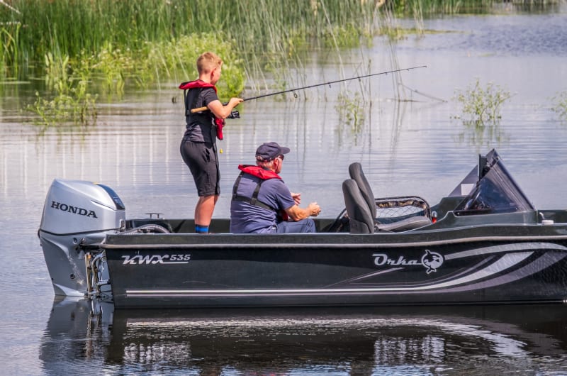 Boy And Man Fishing On Motorboat