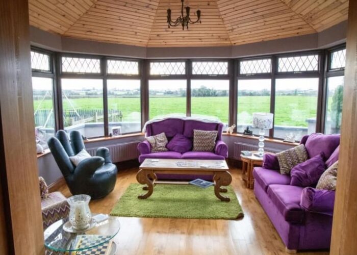 Conservatory Interior With Purple Sofas And Garden View