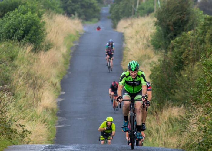 Cyclists riding on rural road through green hills