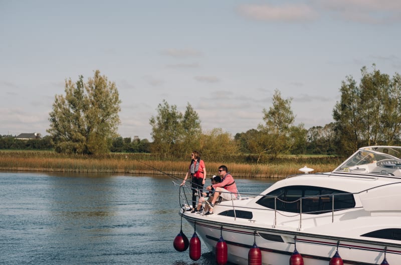 Family Fishing From Bow Of White Yacht