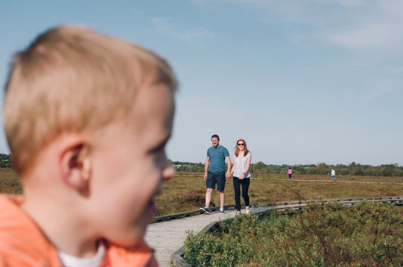 Family Walking On Boardwalk In Nature