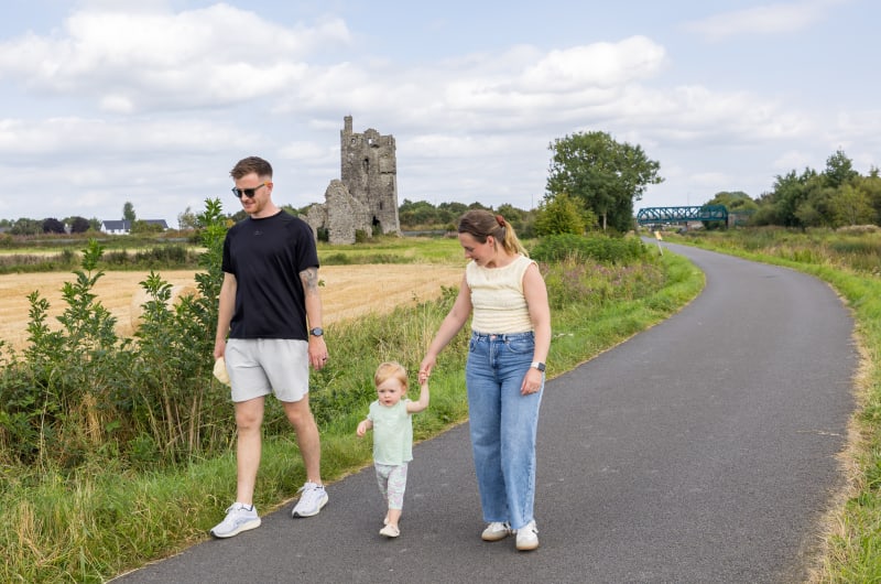 Family Walking On Path Near Stone Ruin