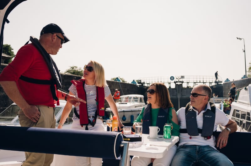 Four People Wearing Life Jackets On A Boat