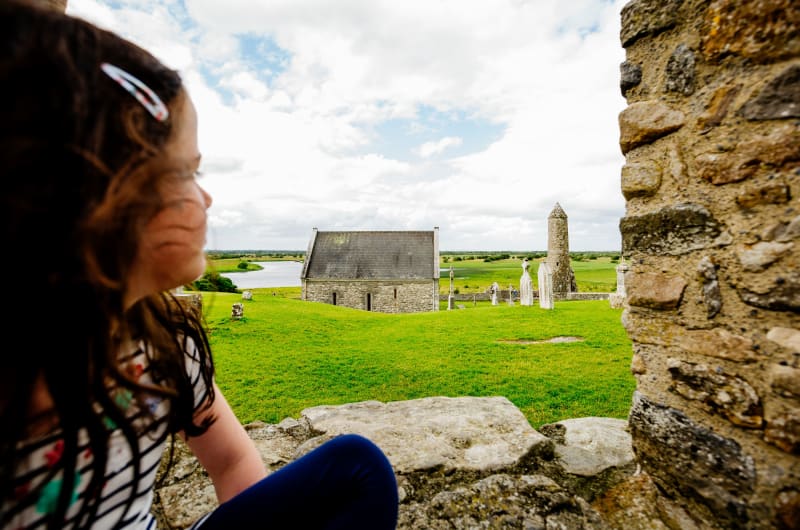 Girl looking at Clonmacnoise monastic ruins and tower