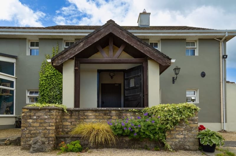 House Entrance With Wooden Porch And Garden