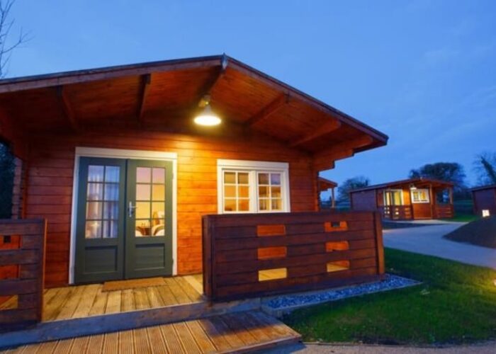 Illuminated Wooden Log Cabins At Dusk