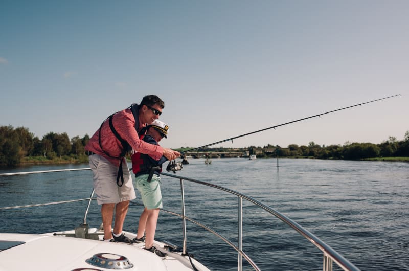 Man And Boy Fishing Together From A Boat