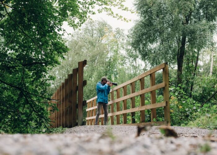 Man In Blue Jacket Taking Photos On Bridge