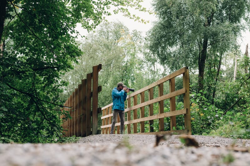 Man In Blue Jacket Taking Photos On Bridge