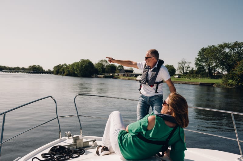 Man Pointing While Woman Relaxes On Motor Boat