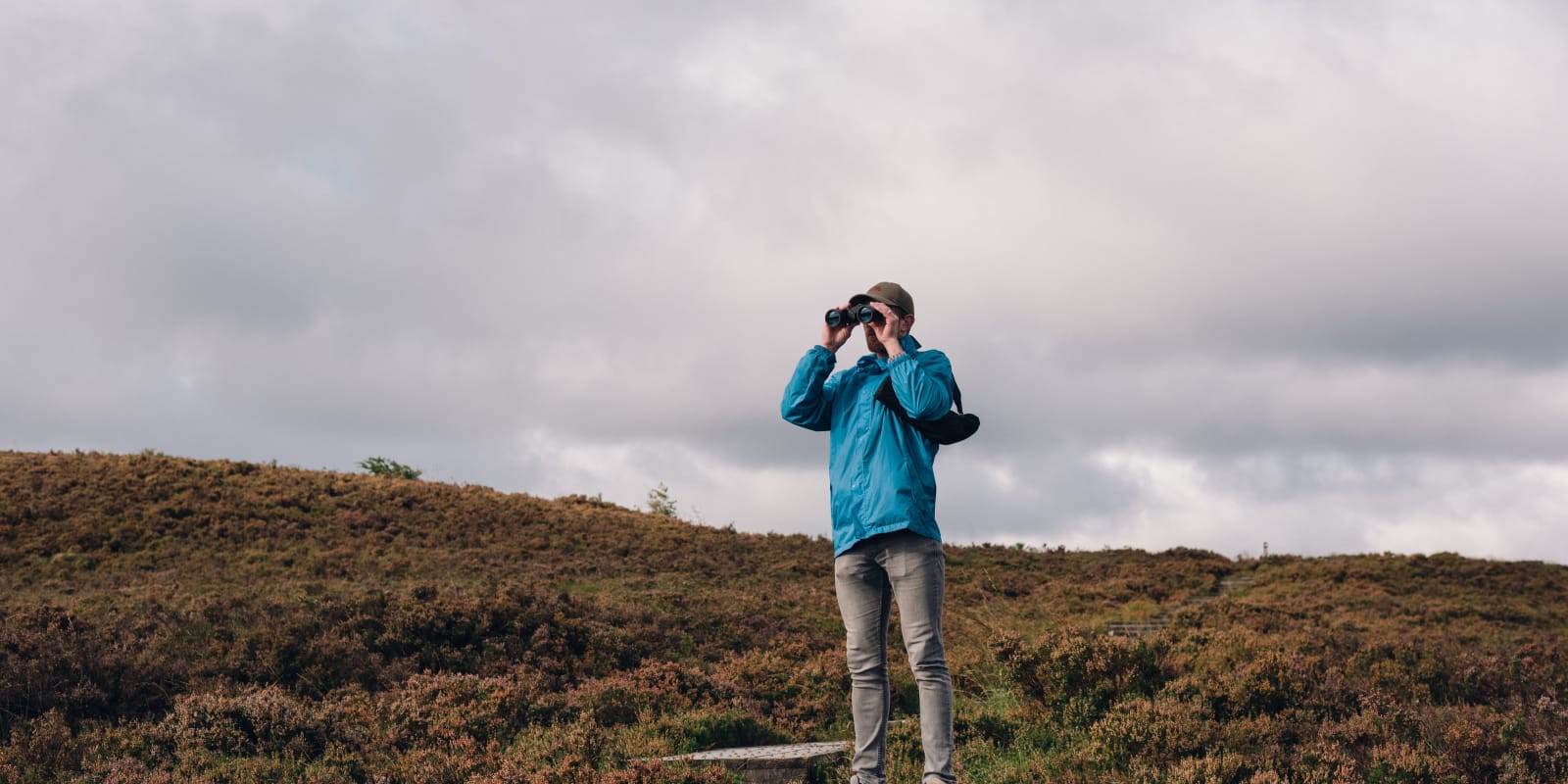 Man With Binoculars Standing On A Moorland Hill