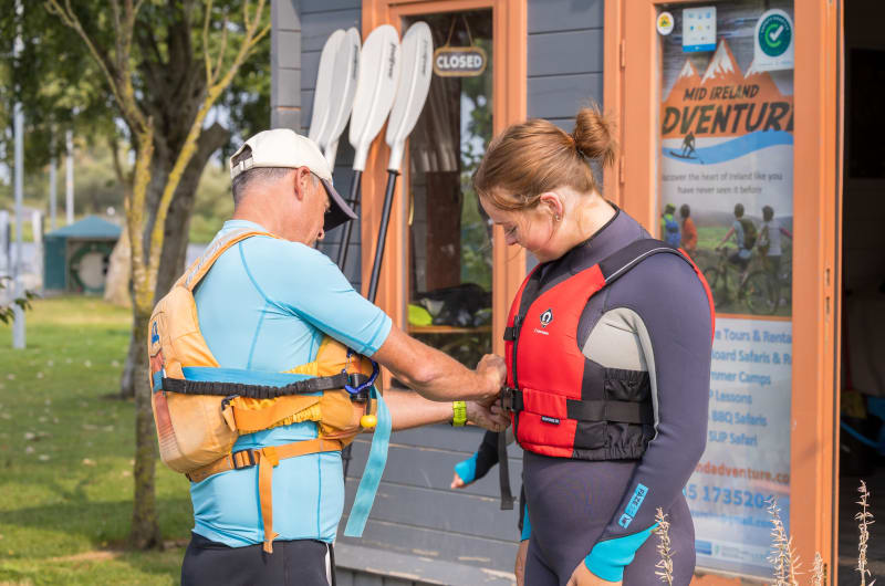Man fitting red life jacket on woman