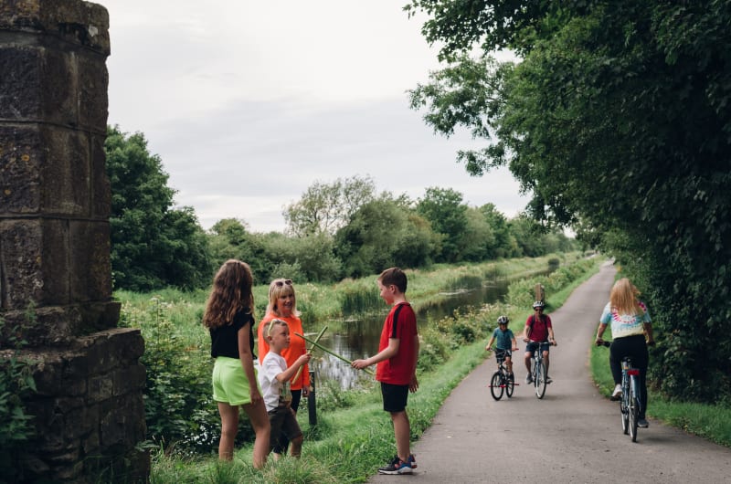 People and children by a scenic canal path