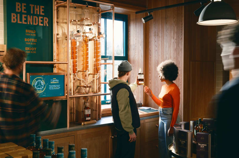 People interacting with Tullamore Dew whiskey blending display
