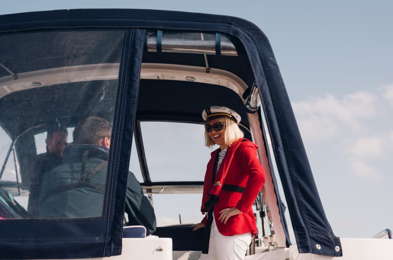 Smiling woman in captain hat on boat