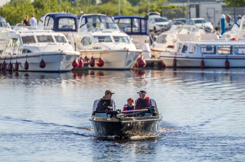 Three people in motorboat near marina docks