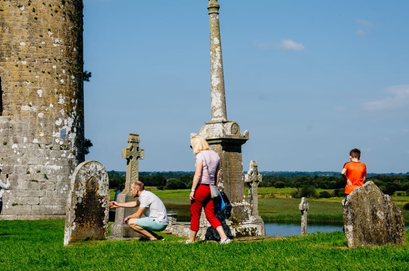 Tourists Exploring Clonmacnoise Monastic Site And Tower