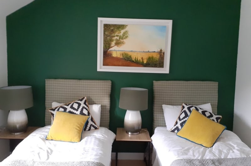 Twin bedroom with green wall and framed painting