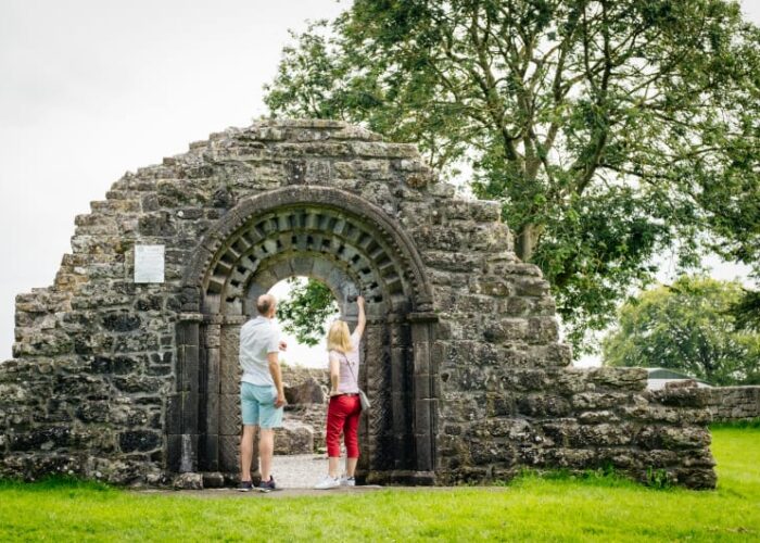 Two People Looking At Carved Stone Ruin Archway
