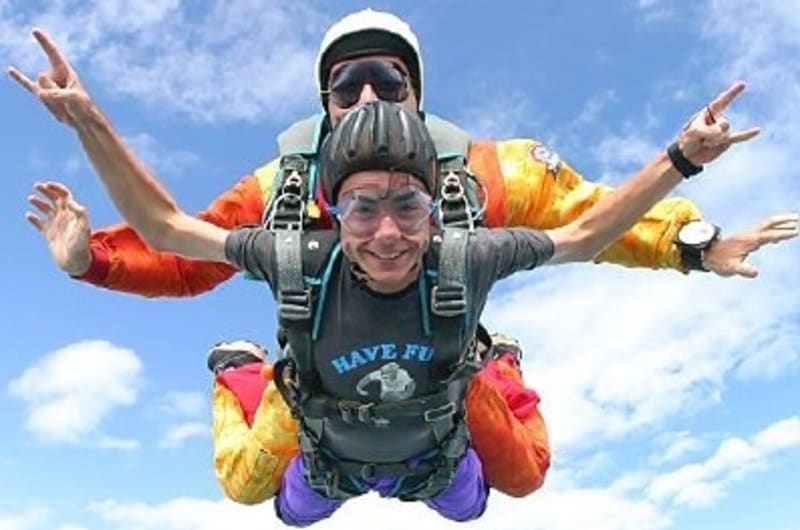 Two People Tandem Skydiving In Blue Sky