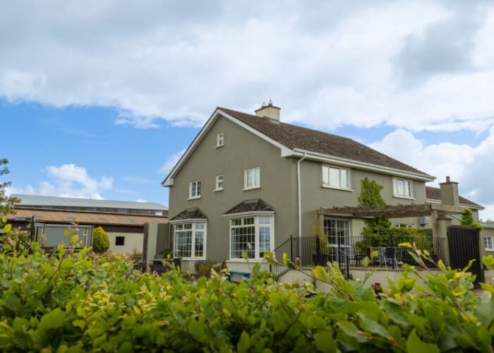 Two Story Gray House With Garden And Outbuildings