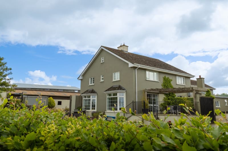 Two Story Gray House With Garden And Outbuildings
