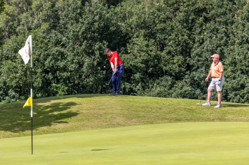 Two golfers playing on a green golf course