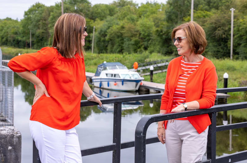 Two women in orange standing near a boat