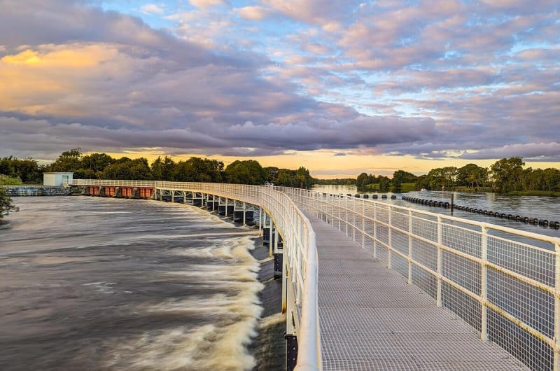 White Walkway Over River Weir At Sunset