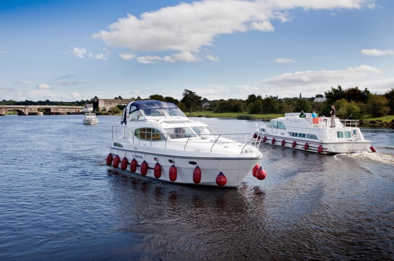 White motor yachts cruising on scenic river