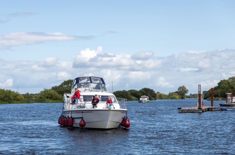 White motorboat with people on bow on river