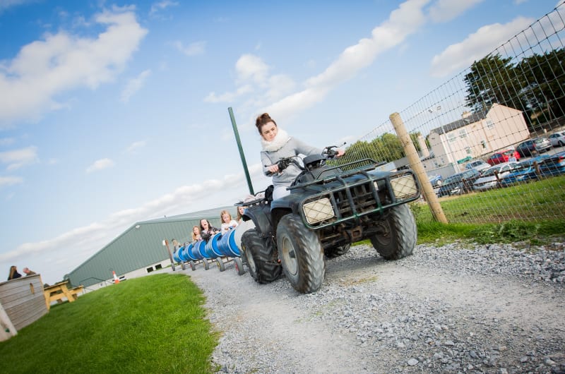 Woman driving quad bike pulling children barrel train