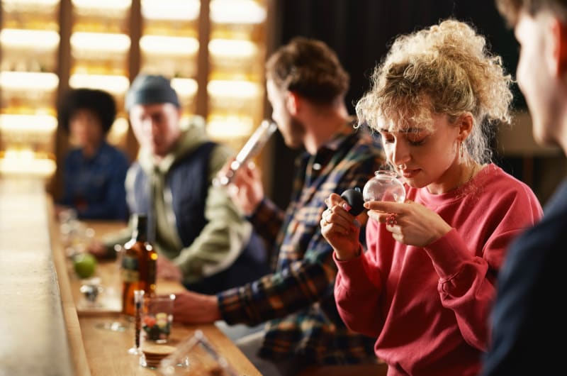 Woman smelling ingredients from glass at a bar