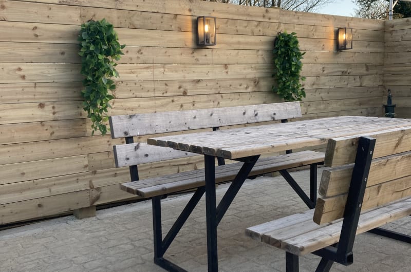 Wooden Picnic Table On Patio With Lighted Fence