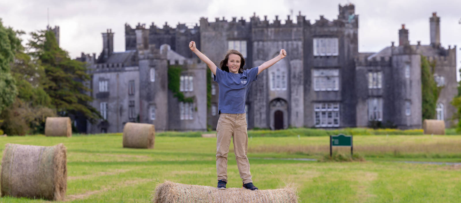 header child standing on haybail in front of castle
