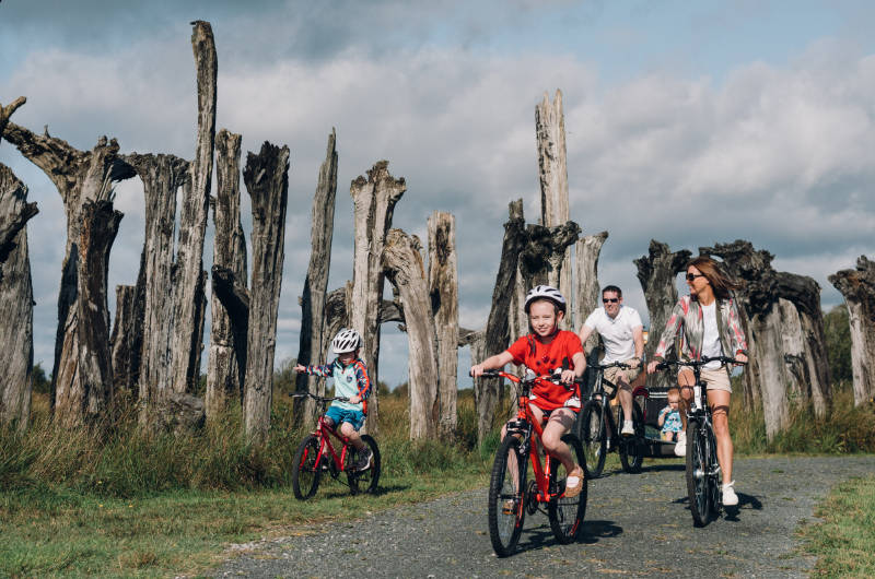 park family on bikes passing dead trees