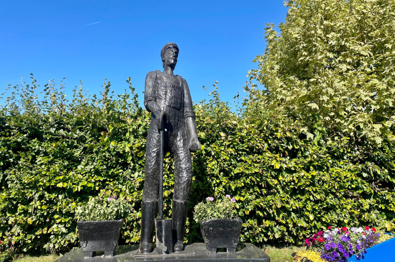 Black Statue Of A Man Holding A Spade e6xphl