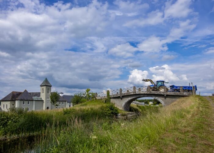Blue Tractor Crossing Stone Bridge Near Building pqwhpj