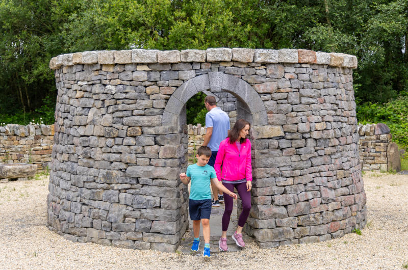 Family Exploring Circular Stone Structure With Arched Doorway