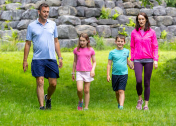 Family Walking Past Large Stone Pyramid In Forest