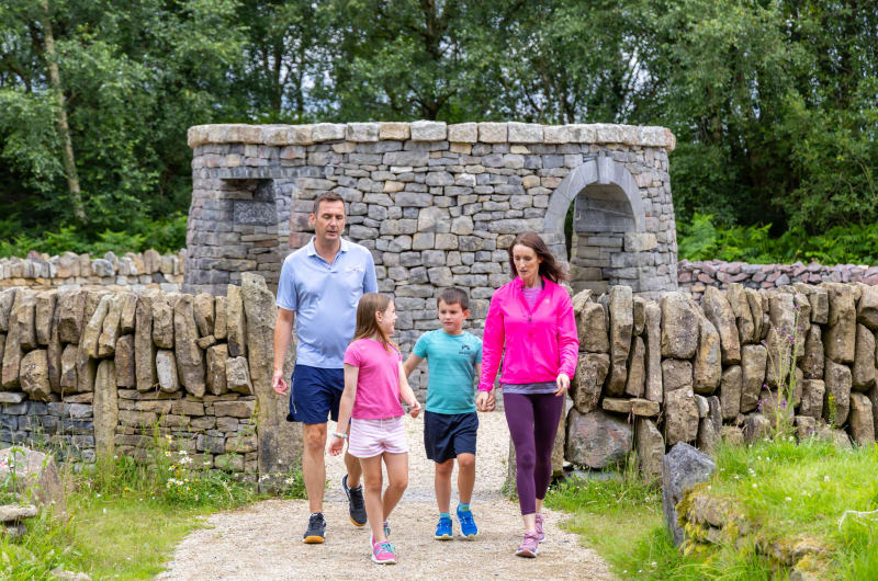Family Walking Past Stone Structure In Nature mutdjw