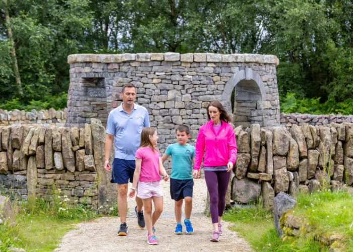 Family Walking Past Stone Structure In Nature mutdjw